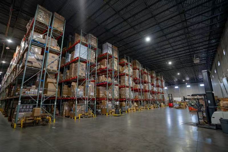 Inside a MashBond self-operated U.S. warehouse — tall pallet racking stacked with inventory and a forklift on the floor